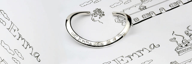 A silver bangle with a hand engraving design and the name Emma on it
