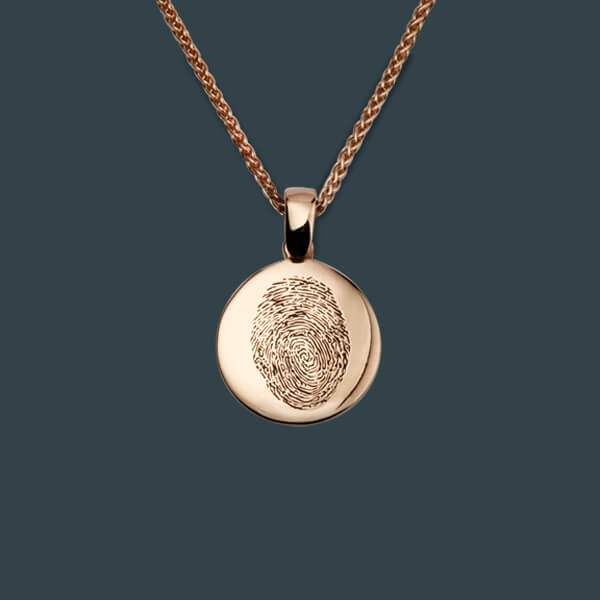 A rose gold pendant with a fingerprint engraved on it.