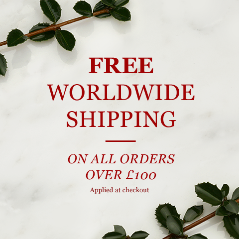 Free worldwide shipping on all orders over £100, in red lettering on white marble with holly sprigs
