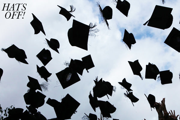 Black graduation caps thrown into a cloudy sky, with Hats off! written in the top corner