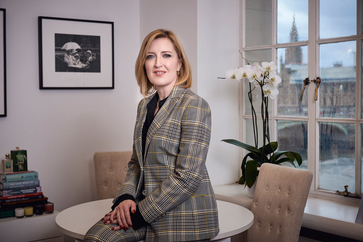 Helen Brocklebank in a checked suit seated at a table beside a window overlooking Westminster