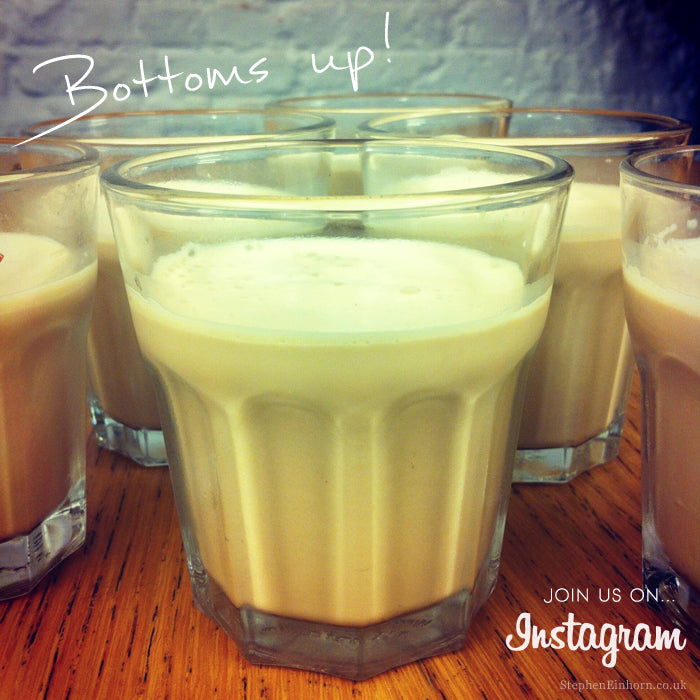 Glasses of iced coffee on a wooden table with 'Bottoms up!' handwritten above and a note to join us on Instagram