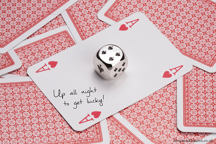 Polished silver dice with spade pips on an ace of hearts, handwritten 'Up all night to get lucky!' on the card