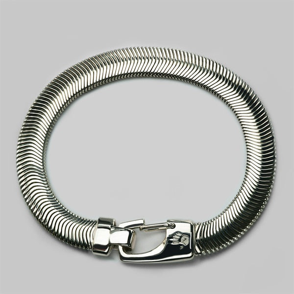 Silver snake chain bracelet with a sculpted silver clasp, laid flat on a grey background