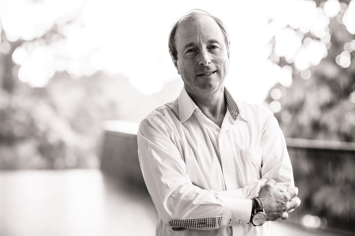 Black and white portrait of Robert Ettinger in a white shirt, hands clasped, trees blurred behind