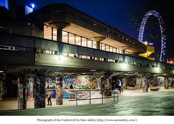The Southbank Undercroft at night, graffiti-covered pillars under the concrete with the London Eye behind