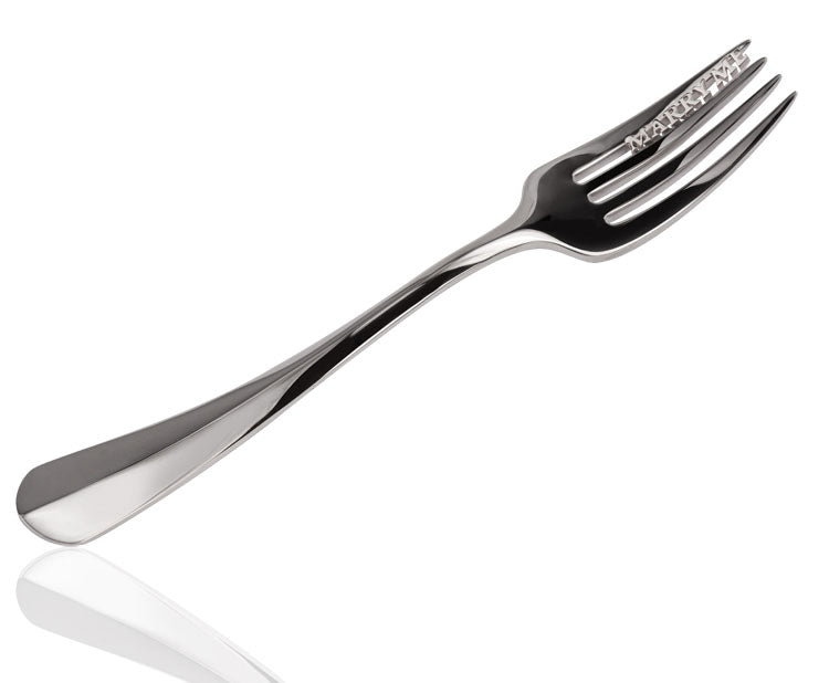 Silver dessert fork with 'Marry Me' pierced into the tines, on a white background