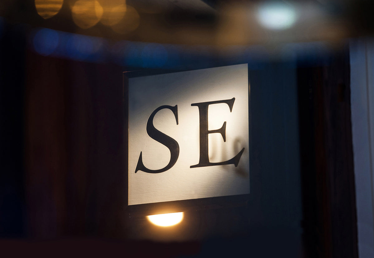 Illuminated SE sign in serif letters outside our London jewellery shop at night