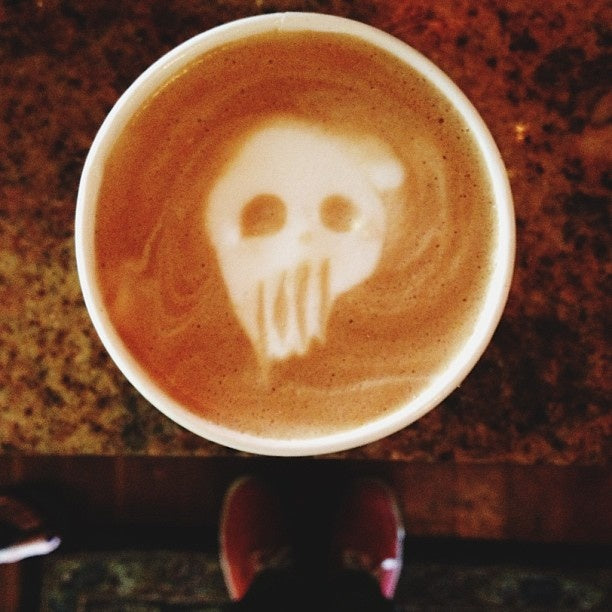 Cappuccino with a skull drawn in the milk foam, seen from above on a granite counter