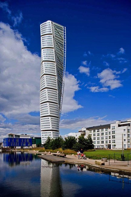 HSB Turning Torso, a white twisting skyscraper in Malmö, reflected in water under a blue sky