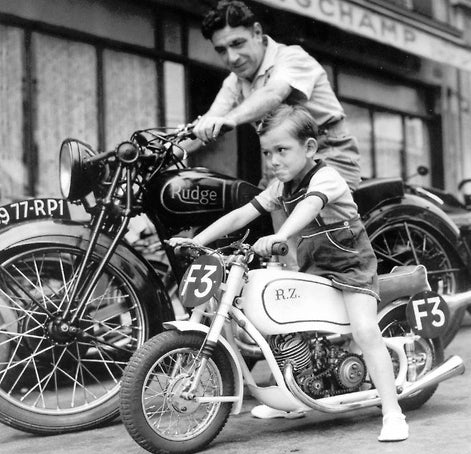 Vintage black and white photo of a father on a Rudge motorbike beside his young son on a small motorbike