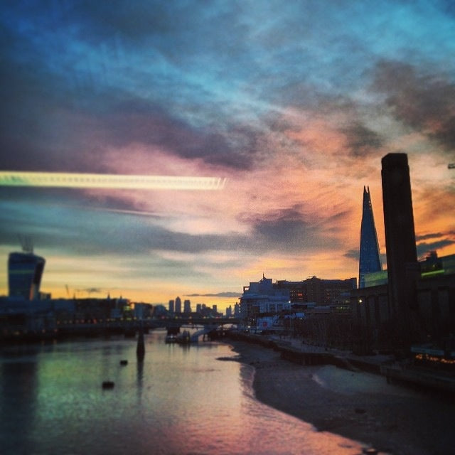 Sunset over the Thames in London, the Shard and the Tate Modern chimney in silhouette against a pink and blue sky
