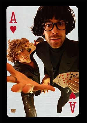 Two performers styled as an ace of hearts playing card, one holding a fan of cards
