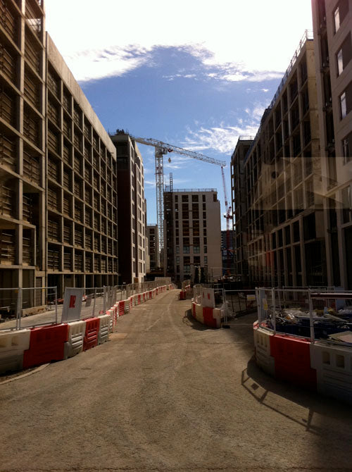 London Olympic Village under construction, tower blocks and cranes either side of a barriered road
