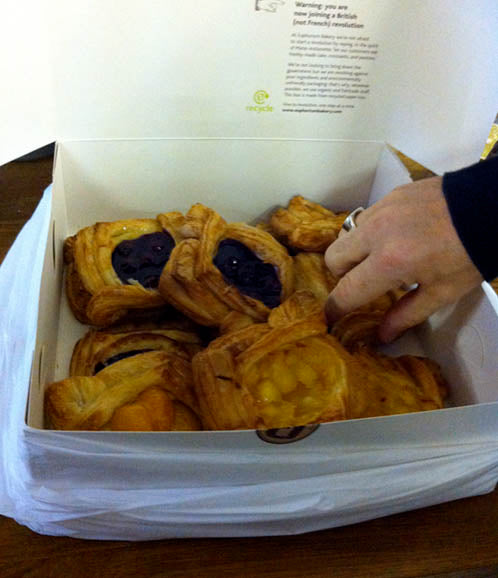 Box of fruit Danish pastries with a hand wearing a silver ring reaching in