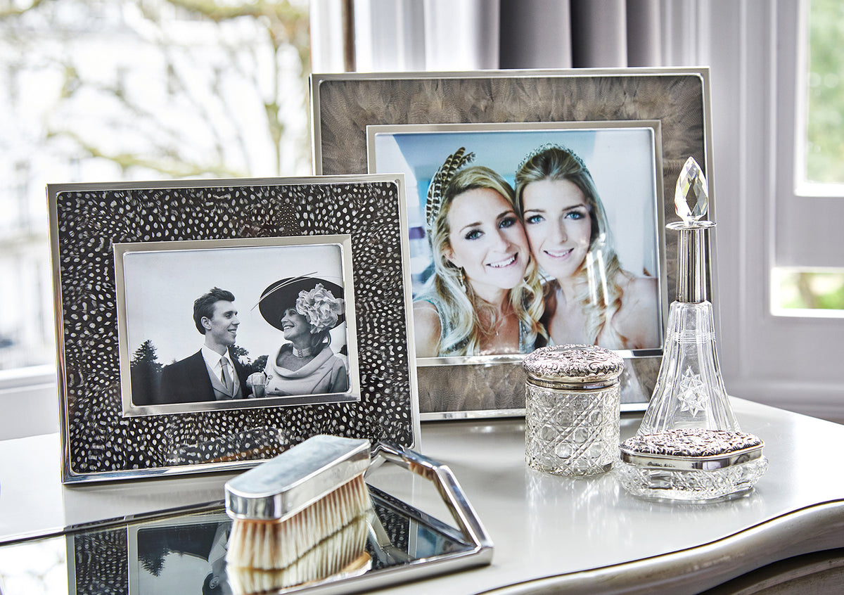 Framed wedding photographs, a cut-glass perfume bottle and a silver-backed brush on a dressing table