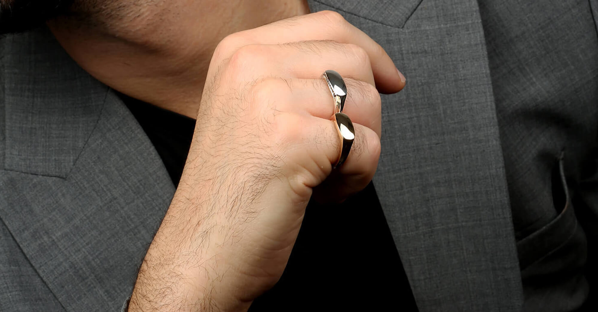 Male hand wearing a silver and a yellow gold slim signet ring.