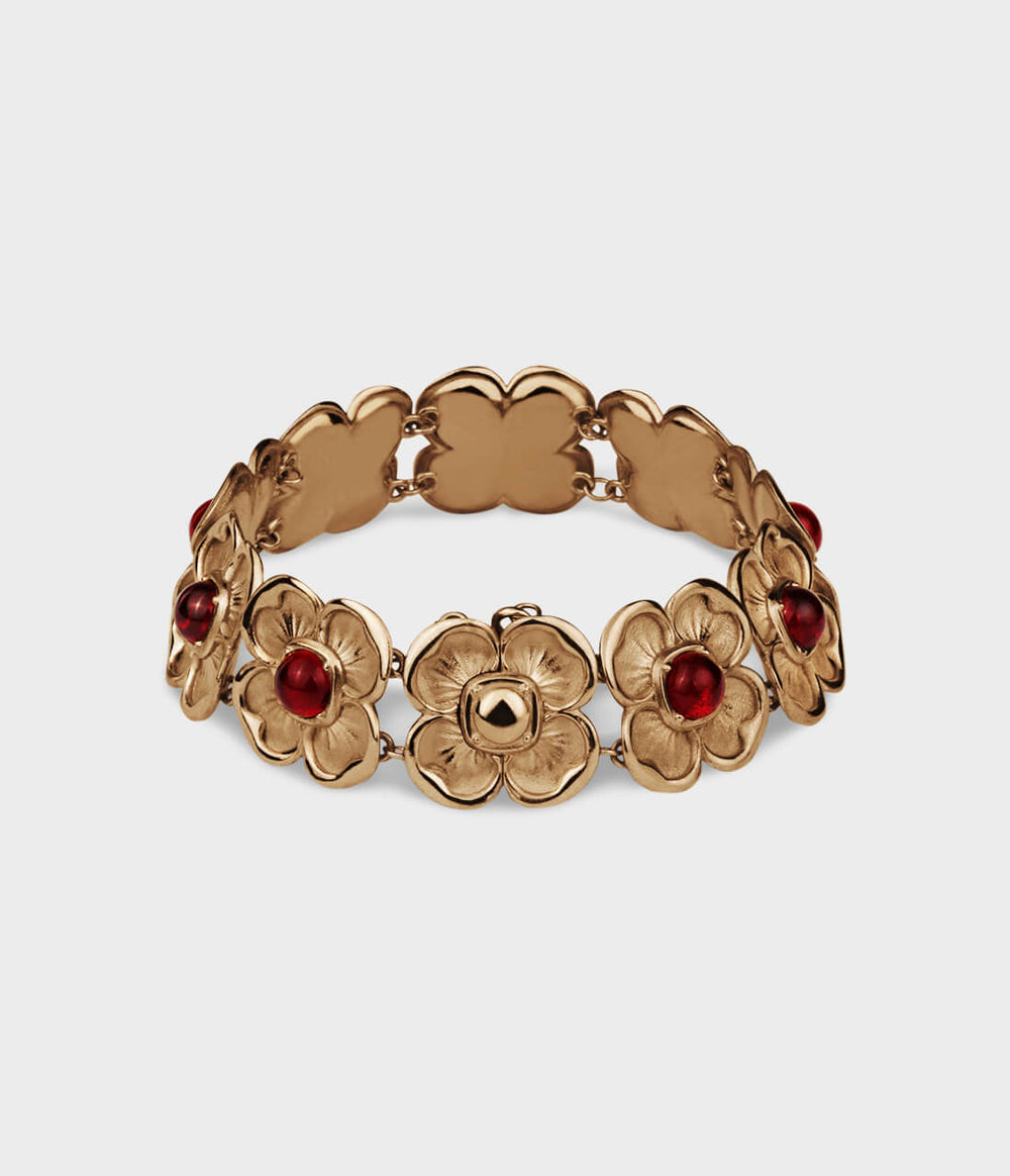 Yellow gold bracelet with interlinking flowers, each inset with a red ruby and one flower that splits in two hiding a magnetic clasp