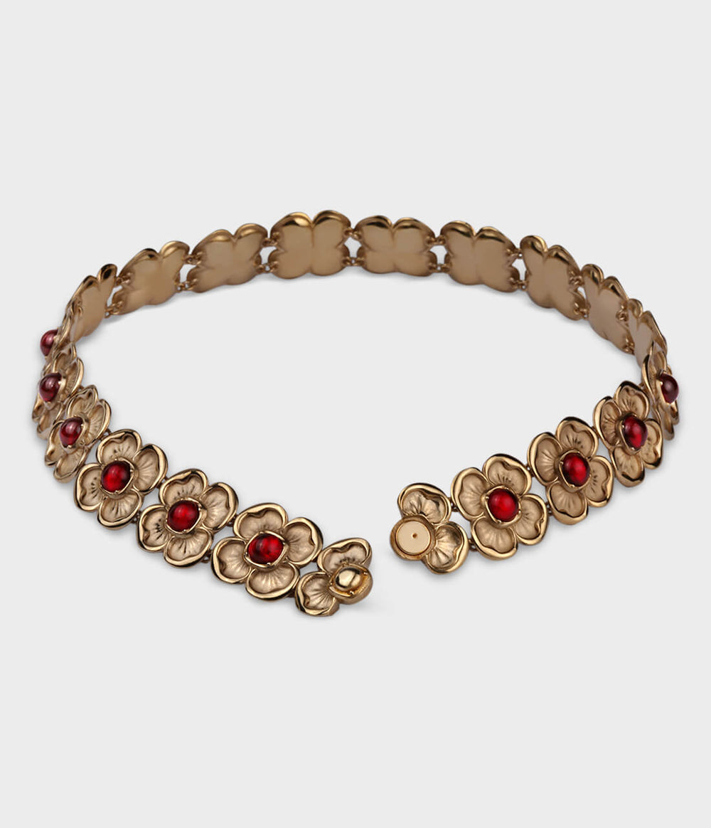 A large ornate choker featuring beautiful interlocking yellow-gold flowers that house a red ruby. the choker is open at the front revealing a hidden magnetic clasp inside one of the flowers