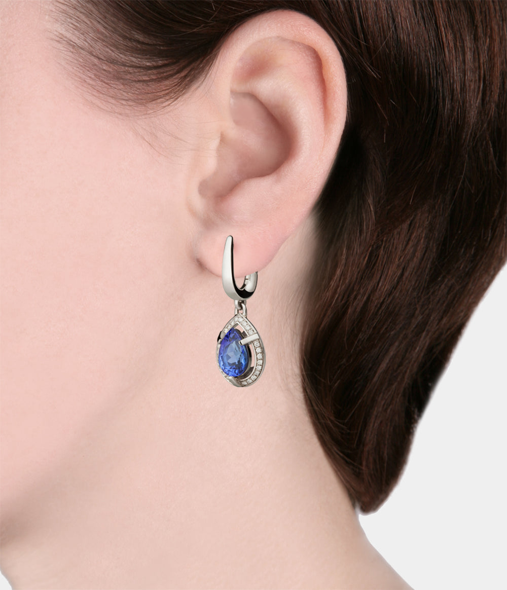 Showing a woman wearing the Tsarina Diamond Halo Earrings with Pear shaped Tanzanite central stones with a halo of diamonds - model view