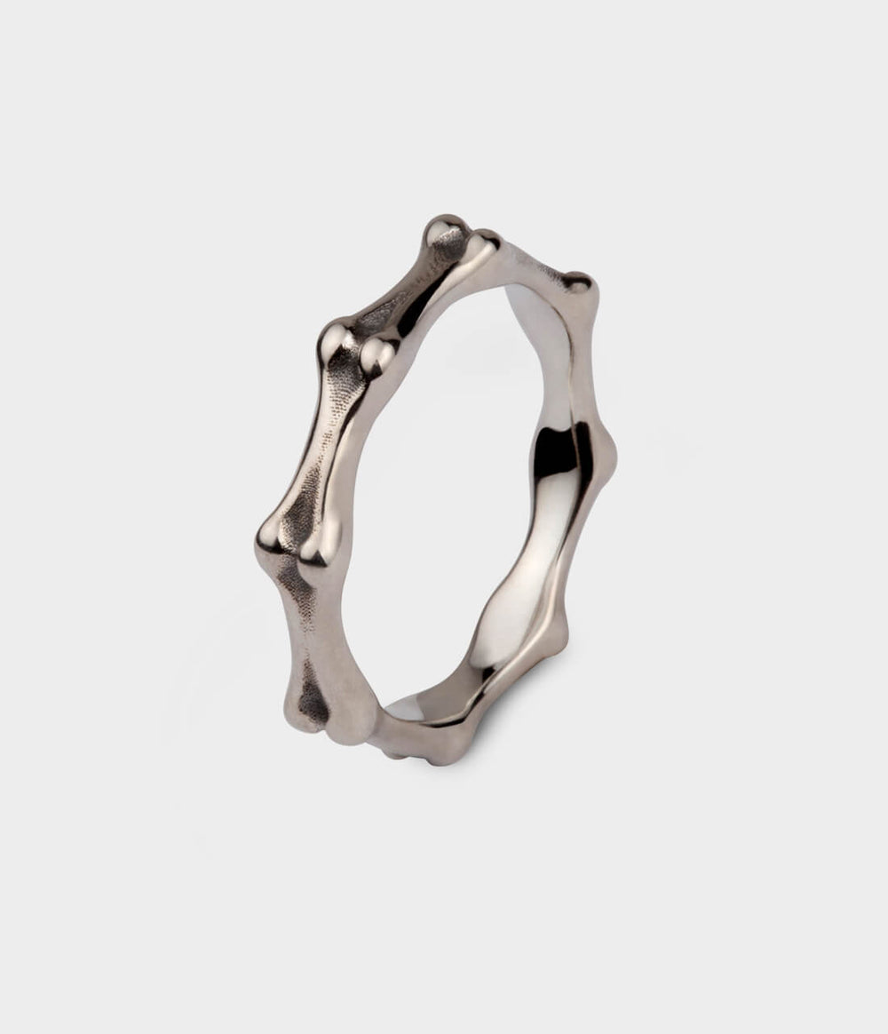 A profile  view of a white gold ring shaped like small bones.