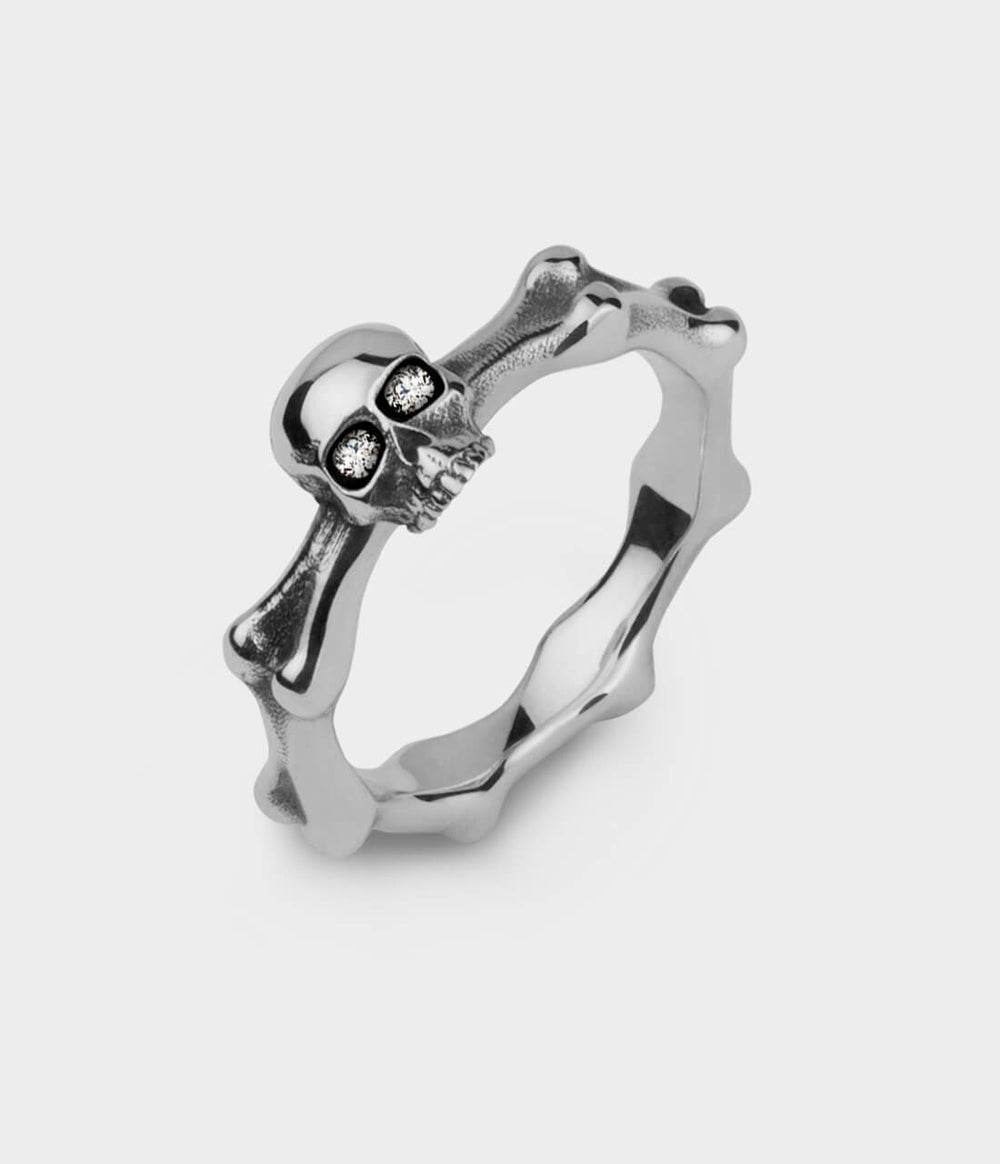 A mini skull and bones ring in sterling silver set with diamond eyes.