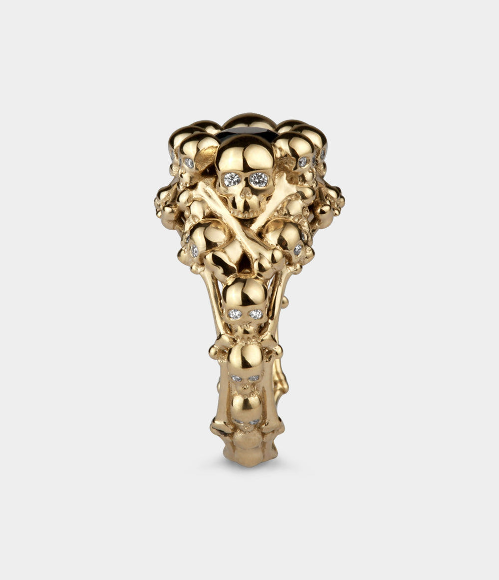 side view of a yellow gold elaborate skull ring made from tiny skulls. All the skulls have had the eyes set with diamonds.