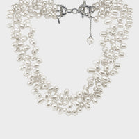 a close up of a three strand white pearl contessa necklace.