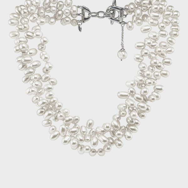a close up of a three strand white pearl contessa necklace.