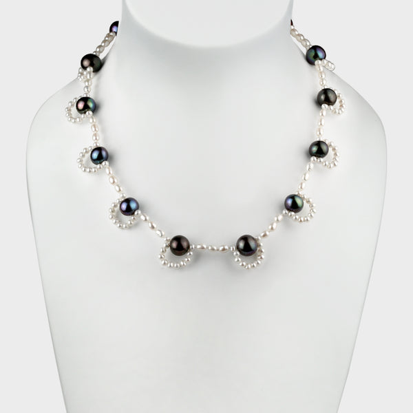 an intricate pearl and silver necklace with loops.