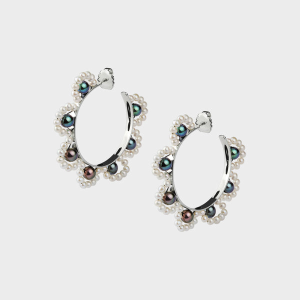close up of silver hoops with an intricate pearl design sewn on.