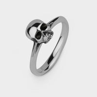 An upright view in close up of a silver small skull ring 
