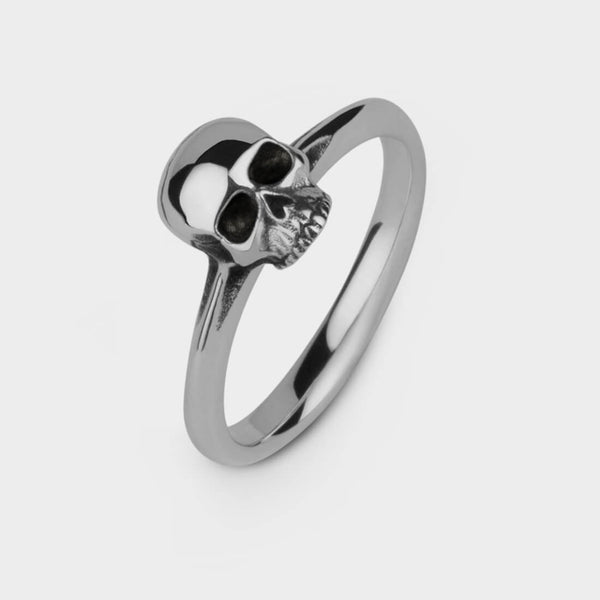An upright view in close up of a silver small skull ring 
