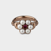 rose gold posy ring seen from the front. The hands on each side of the setting are visible. The ring is round white akoya pearls and a ruby.