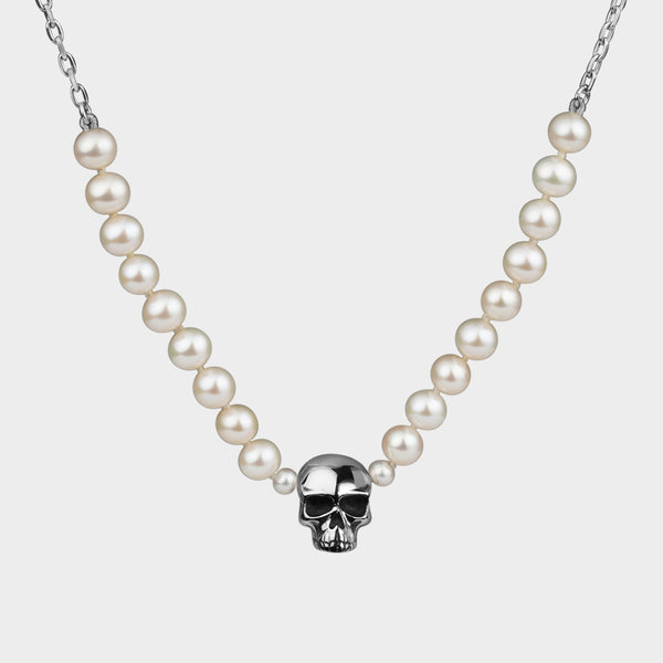 A close up of a silver skull necktie that has been strung on  white pearls.