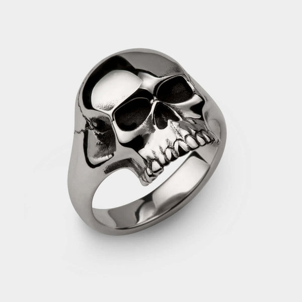 A close up of an anatomically correct highly polished silver skull ring. 