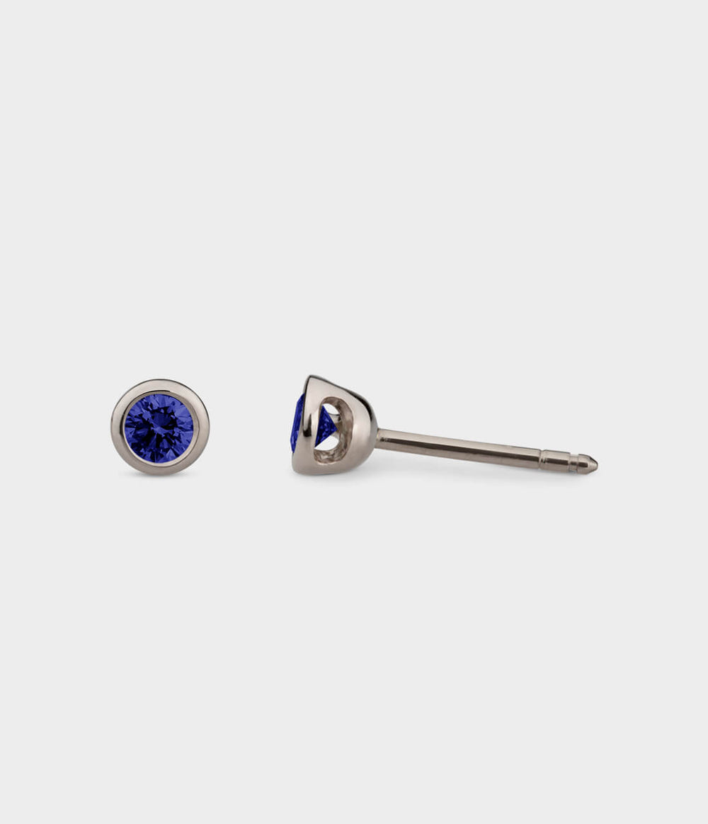 front and side view of white gold small halo studs with blue sapphires