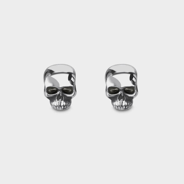 An enlarged picture of small silver skull stud earrings.