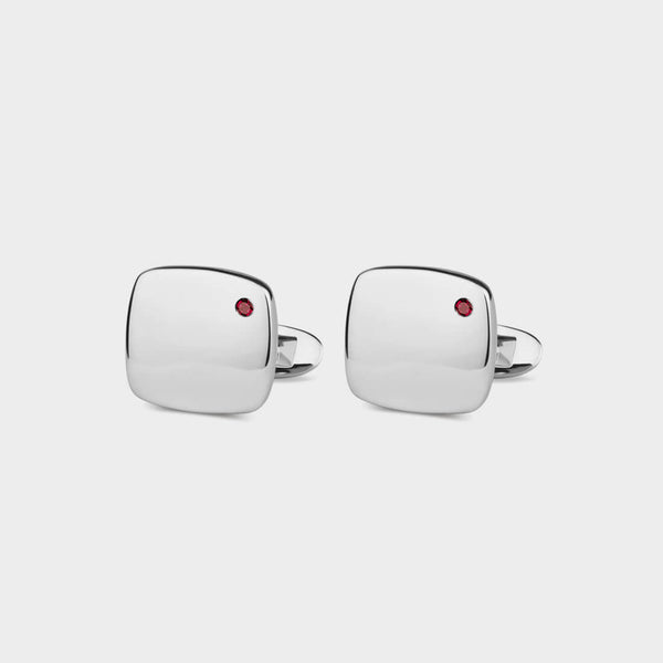 a pair of silver Soho Cufflinks with a ruby set into them