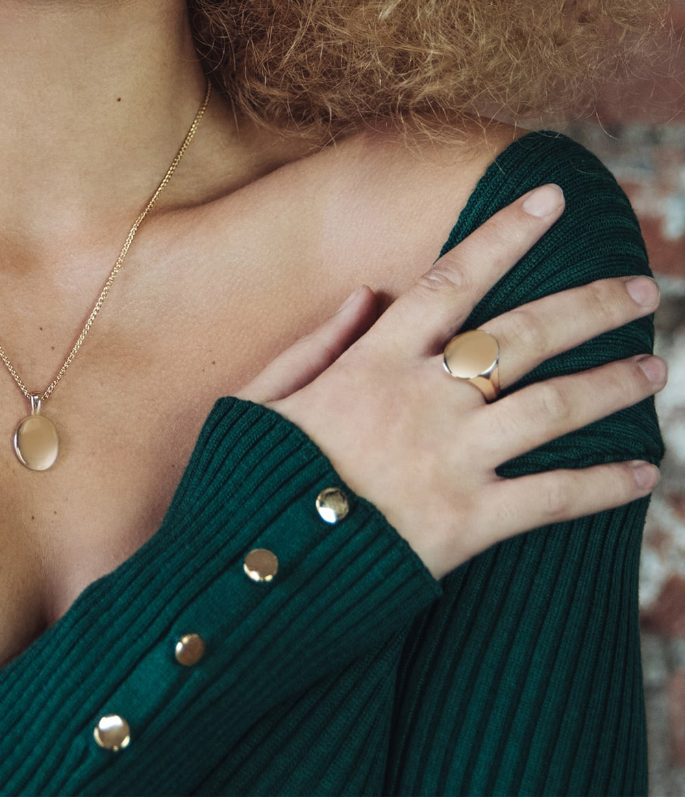 a women wearing a signet pendant and ring in yellow gold